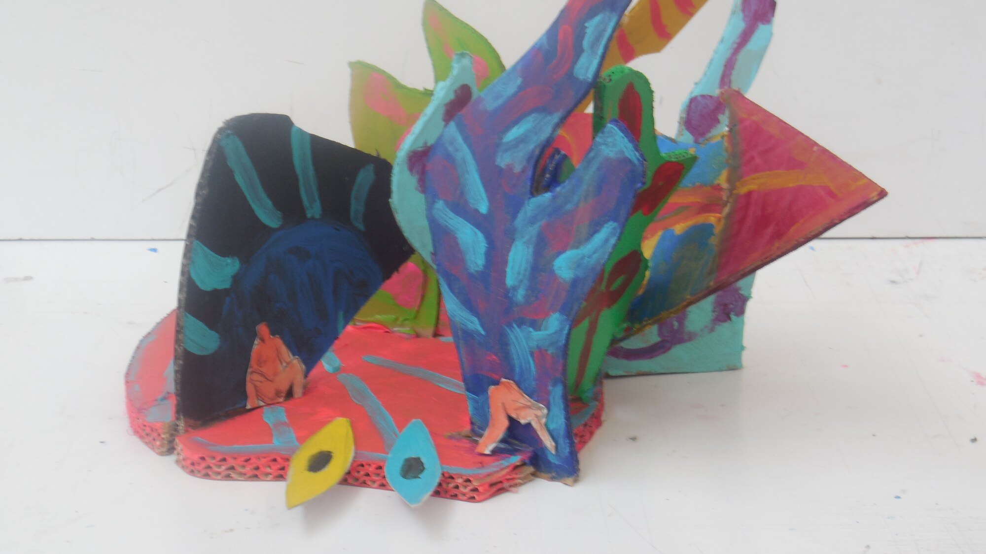 Sculpture en carton peint aux feuilles bleues, vertes et roses sur socle rose, petites figures collees, oeuvre de Marc Sardina