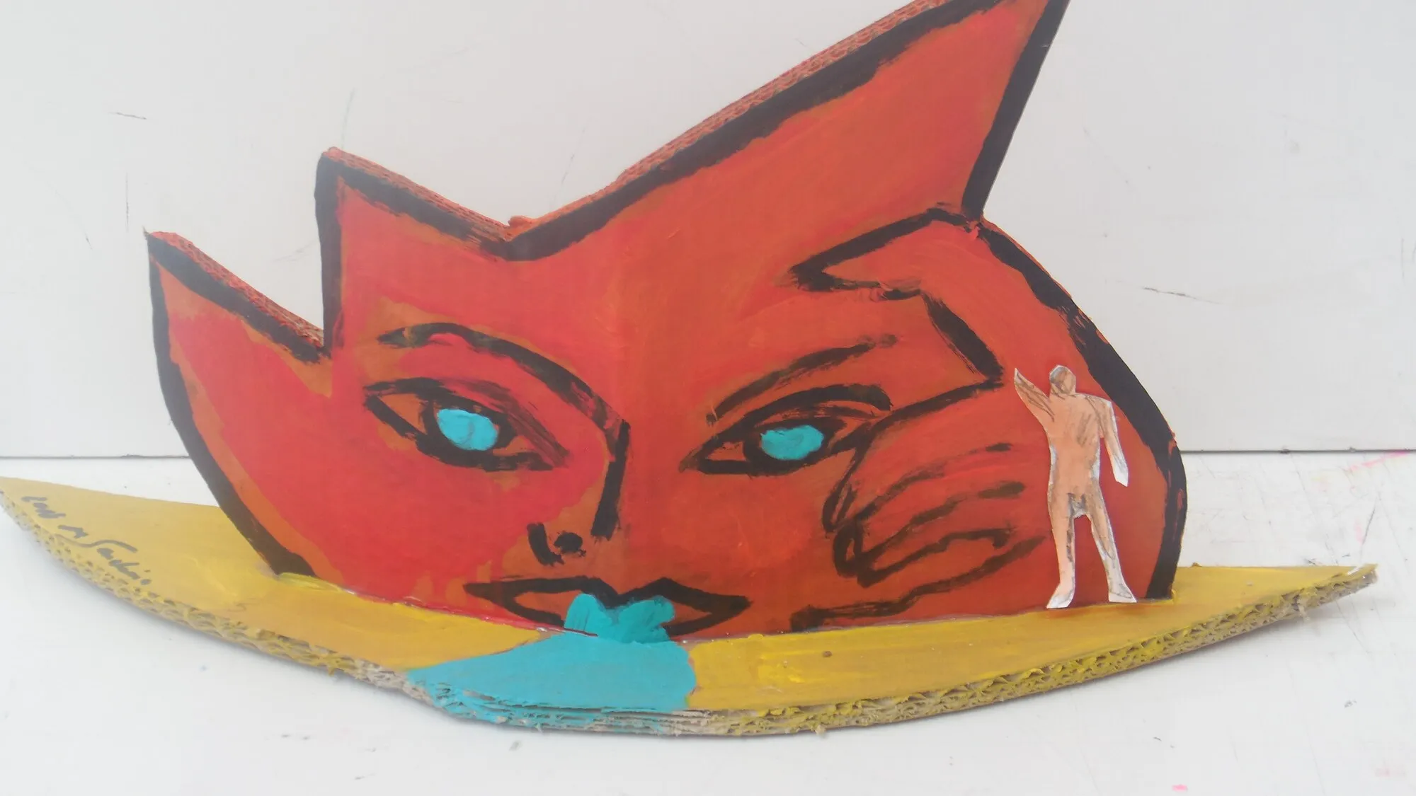 Sculpture en carton, visage rouge aux yeux turquoise sur une barque jaune, petite figure nue, oeuvre de Marc Sardina