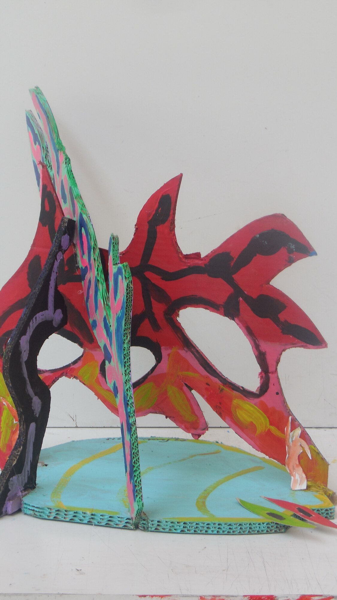 Sculpture en carton peint, feuilles rouges a nervures noires sur socle turquoise, oeuvre de Marc Sardina