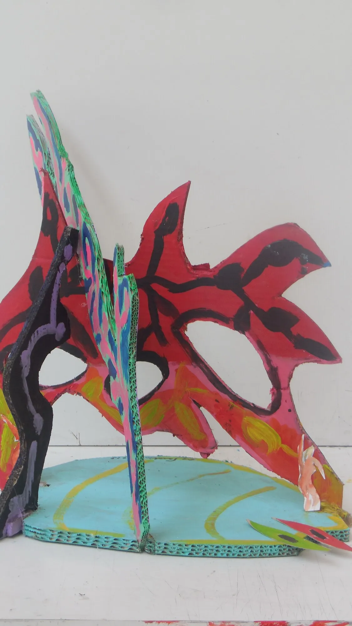 Sculpture en carton peint, feuilles rouges a nervures noires sur socle turquoise, oeuvre de Marc Sardina
