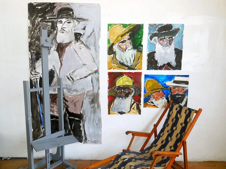 Grande toile grise sur chevalet et quatre petits portraits colorés d'hommes à chapeaux dans un atelier, installation de Marc Sardina