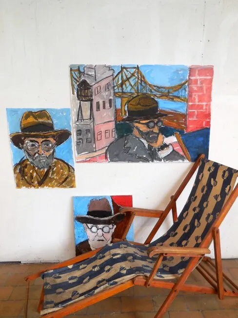 Trois portraits d'hommes à chapeaux, bleu et ocre, dont un devant New York, dans un atelier avec chaise longue, installation de Marc Sardina